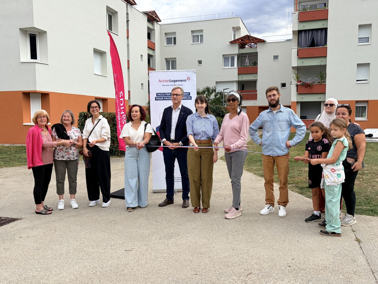12 personnes coupent le ruban pour inaugurer la résidence les roseaux à Vizille avec la résidence en arrière plan.