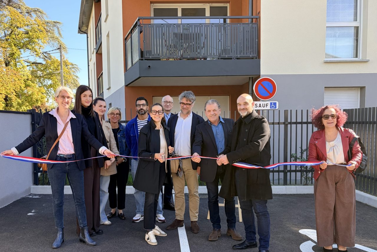 Groupe de personnes coupan un ruban d'inauguration devant une résidence
