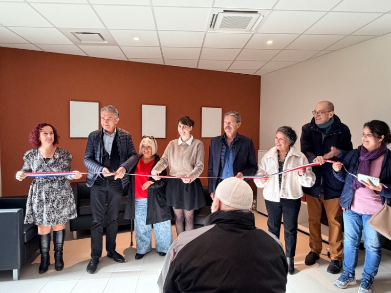 Cérémonie d’inauguration dans une salle intérieure, avec plusieurs personnes tenant ensemble un ruban tricolore avant sa coupe.